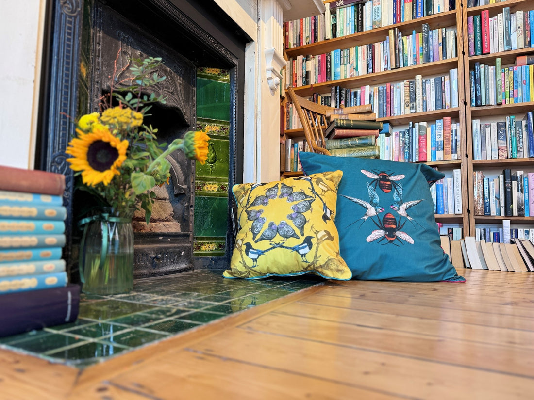 Velvet, colourful cushions by a fireplace with books